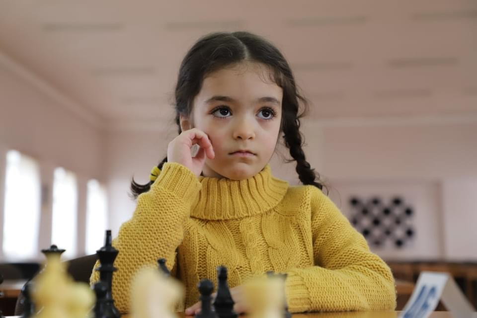 Lucy sitting at a chessboard